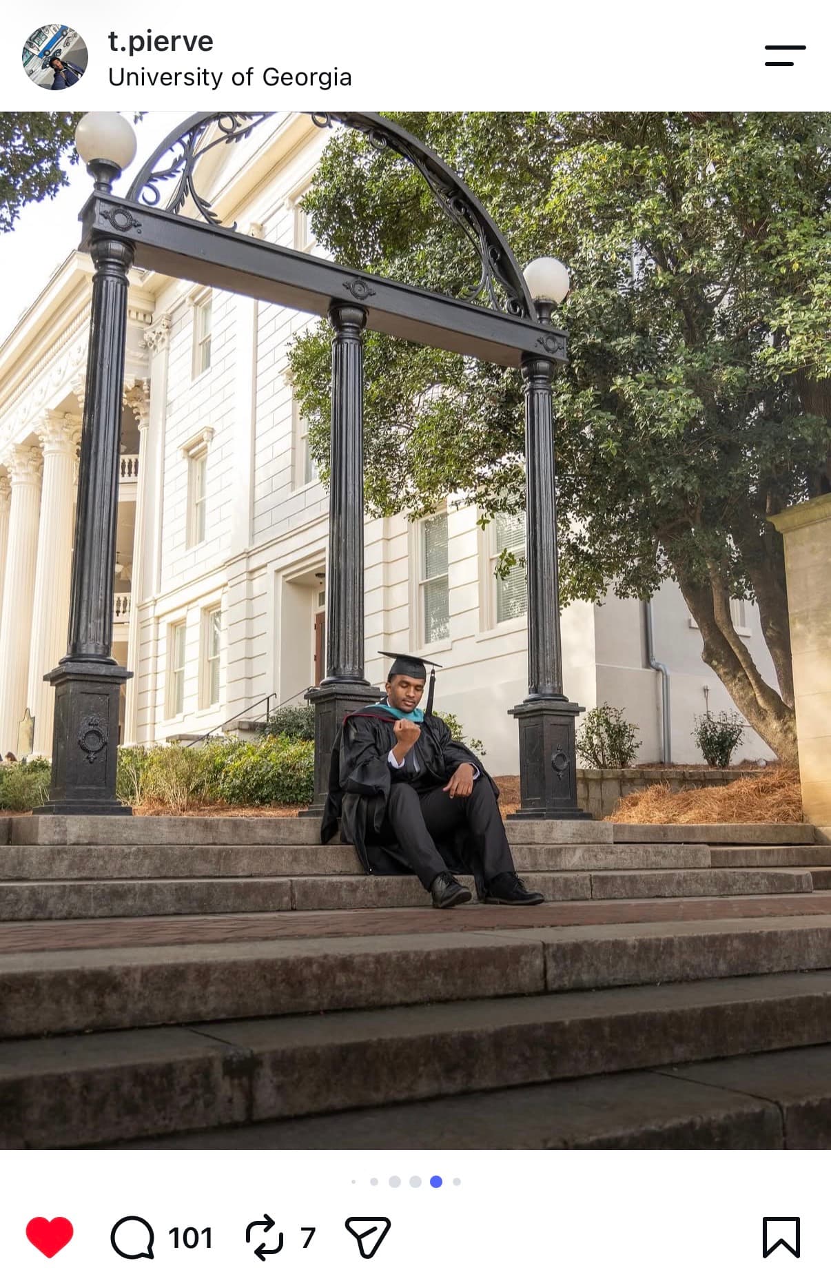 Instagram post: graduate seated on the steps beneath the UGA Arch, admiring his class ring
