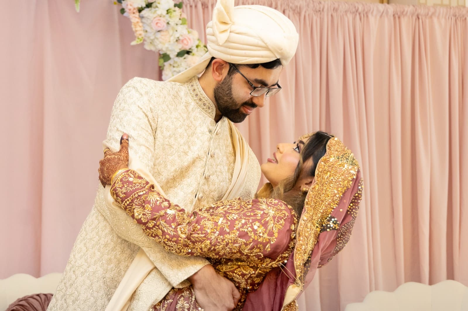 Bride twirling under her groom's arm in a gold-embroidered lehenga, dupatta in motion