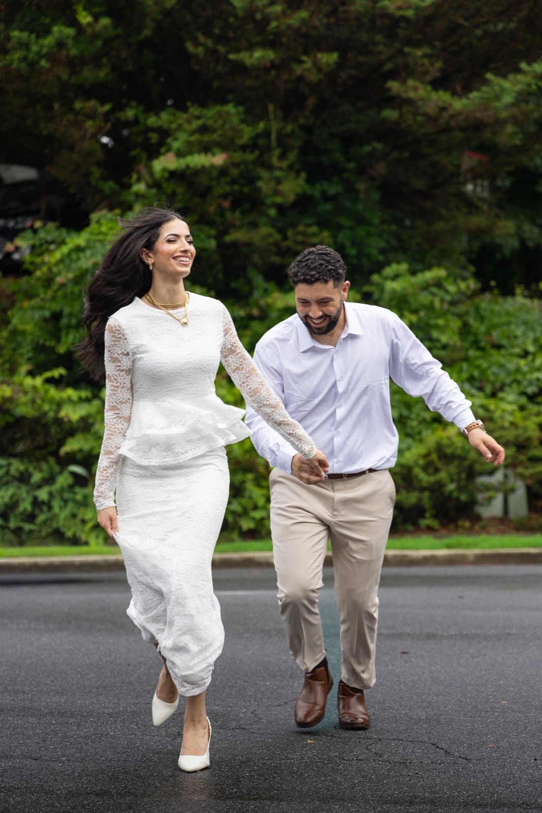 Couple running hand in hand down the street, both mid-laugh