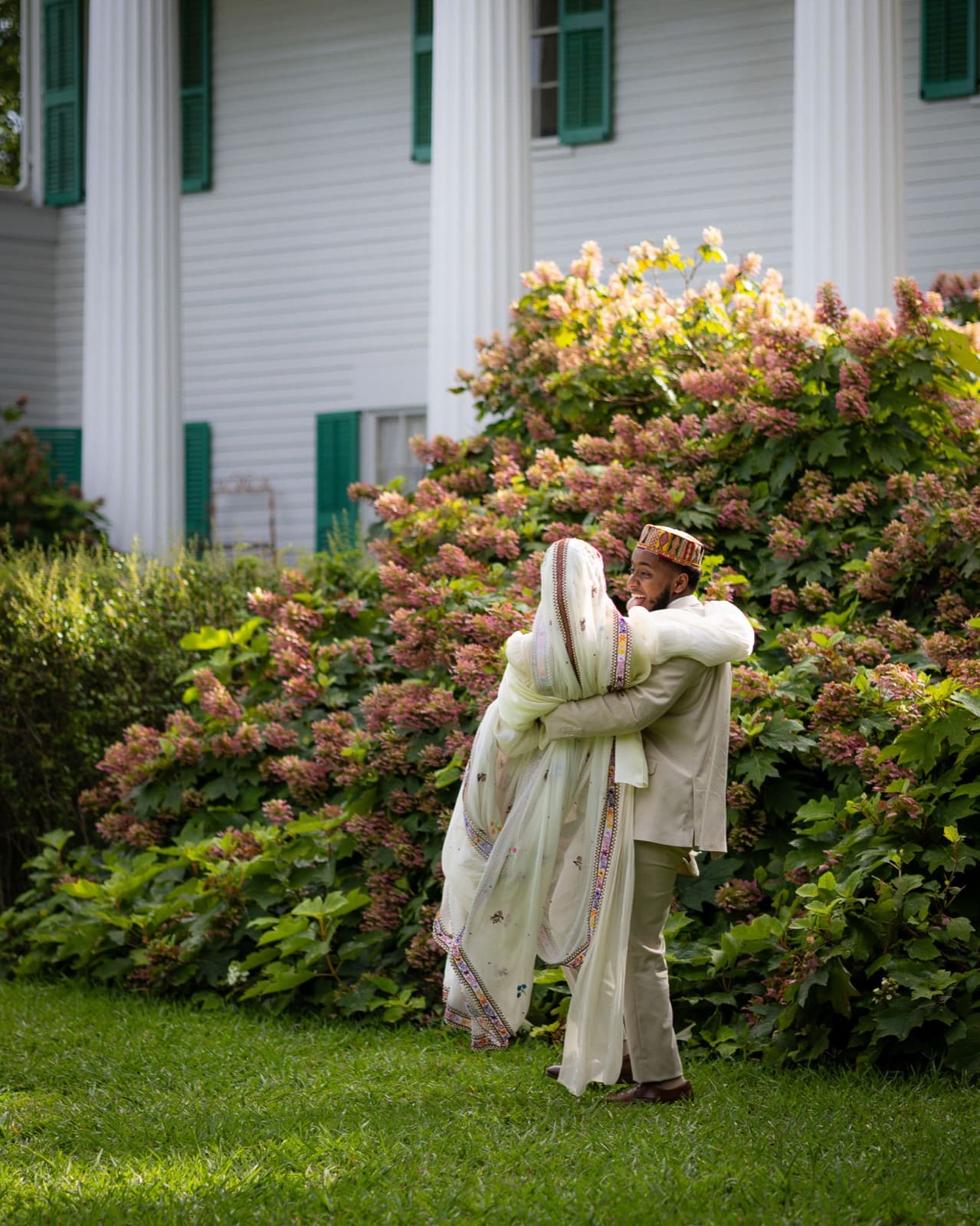 Couple wrapped in an embrace beside blooming hydrangeas, her embroidered shawl catching the light