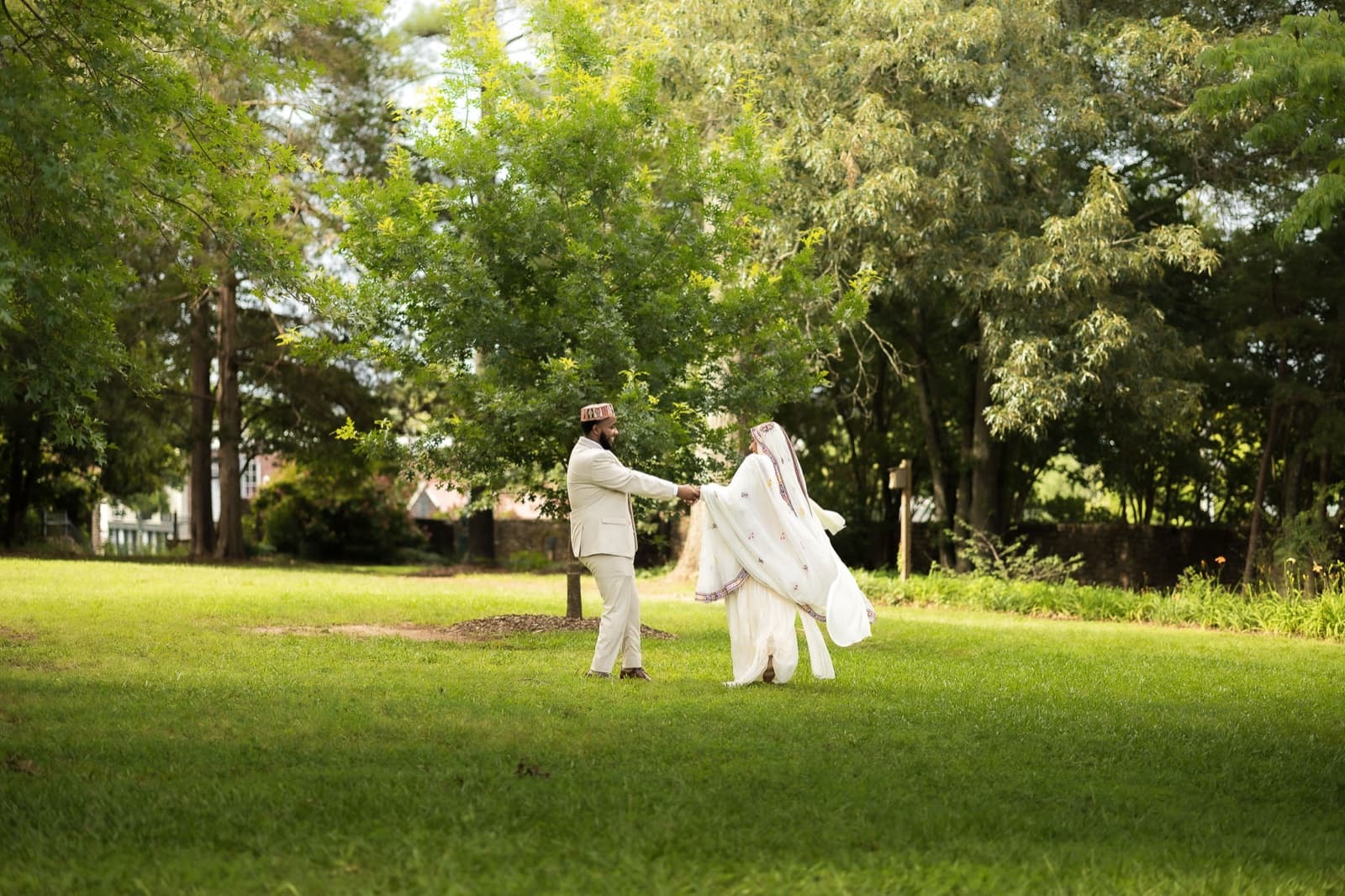 Couple dancing on the open lawn, her white gown and veil catching the summer light