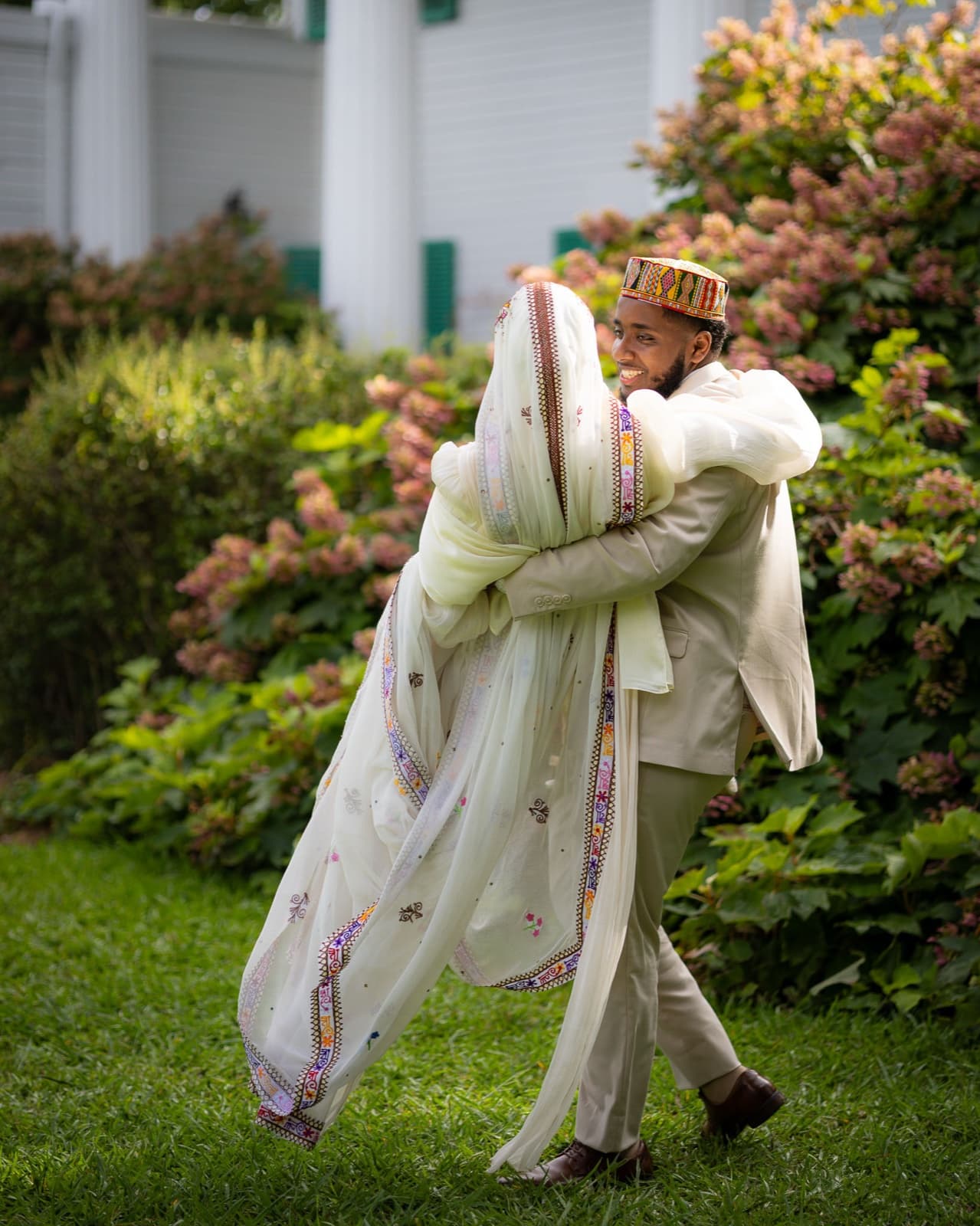 Groom sweeping his bride into a hug, her embroidered shawl swinging with the spin