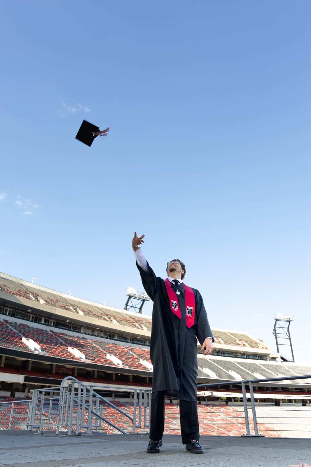 Cap spinning high above a graduate on the concourse of Sanford Stadium