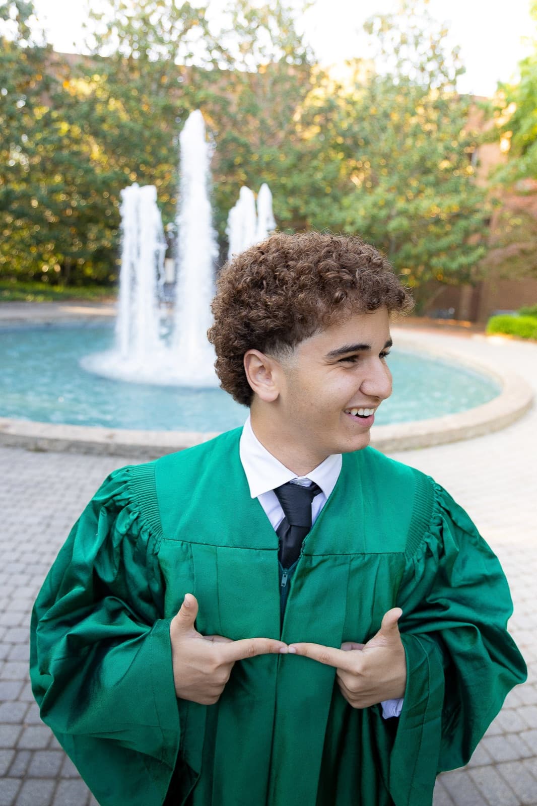 Grad in a green gown laughing by the Herty Field fountain